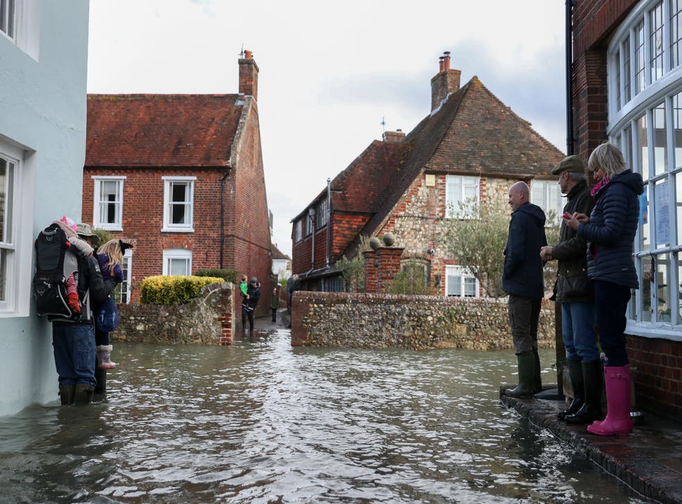 People navigate a flooded street in Bosham, West Sussex on Sunday