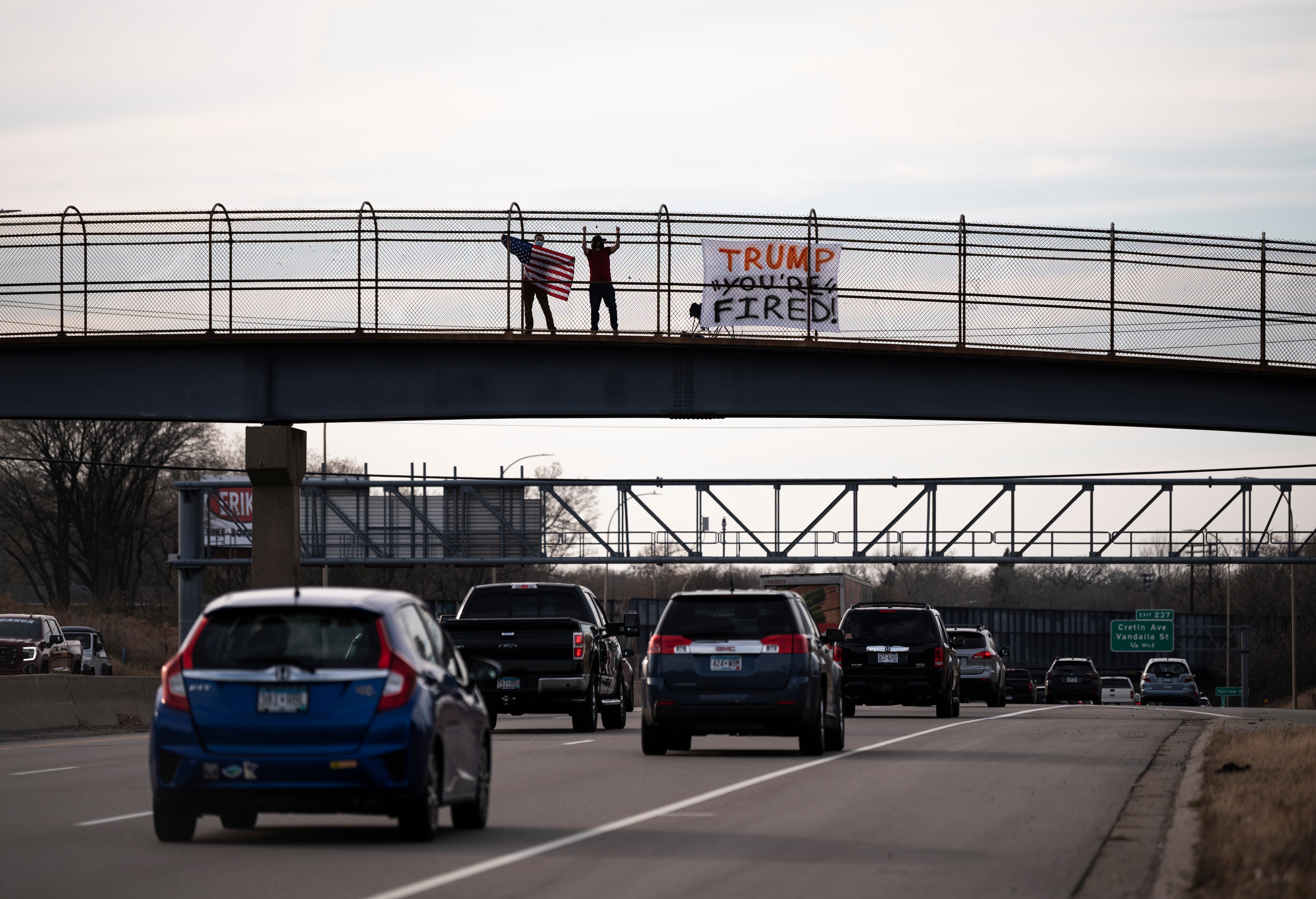 A man waves an American flag on a pedestrian bridge above highway I-94 on November 7, 2020 in St. Paul, Minnesota.