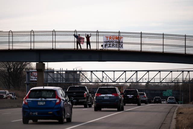 A man waves an American flag on a pedestrian bridge above highway I-94 on November 7, 2020 in St. Paul, Minnesota. 