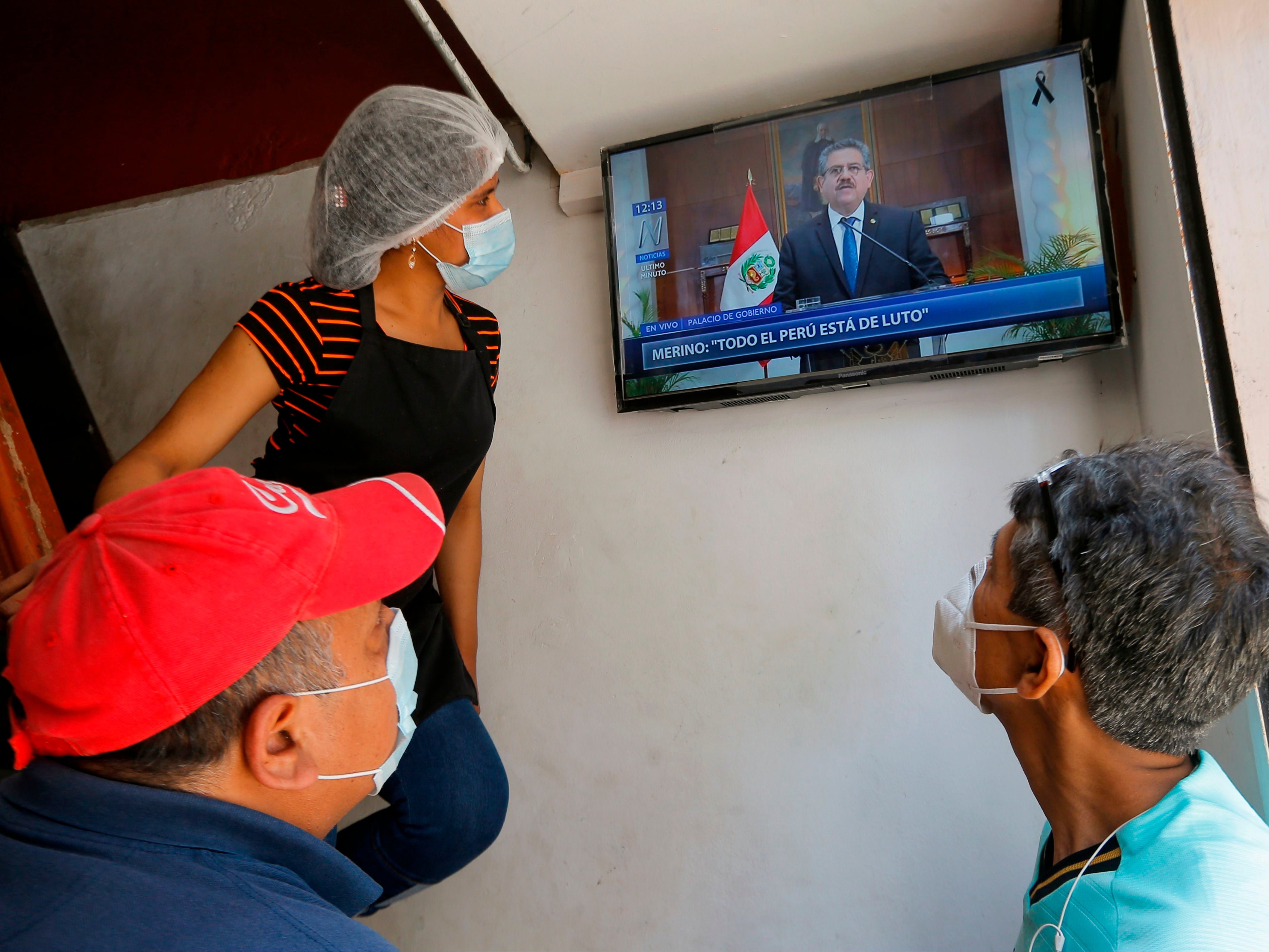 People in a snack bar in Lima watch as Peruvian interim president Manuel Merino announces he is standing down in a televised message on Sunday