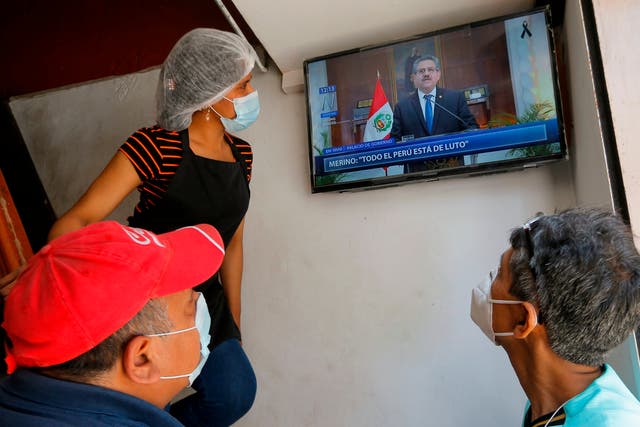 <p>People in a snack bar in Lima watch as Peruvian interim president Manuel Merino announces he is standing down in a televised message on Sunday</p>