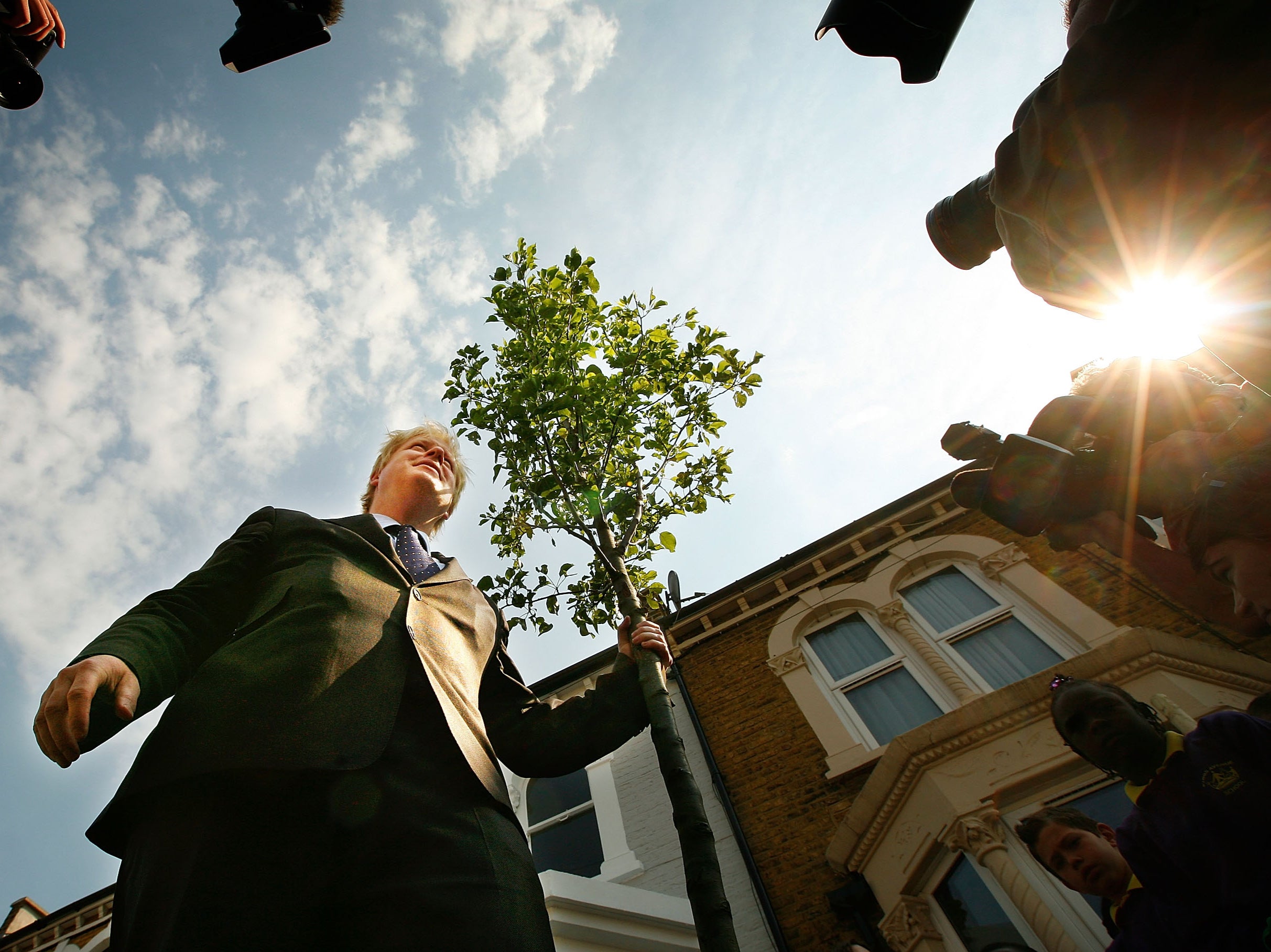 Boris Johnson stands beside a tree he planted in 2008, as part of an initiative during his tenure as London mayor
