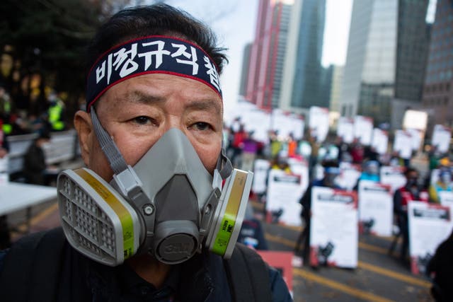 <p>A union member wears a gas mask during protests for better working conditions in Seoul this week</p>