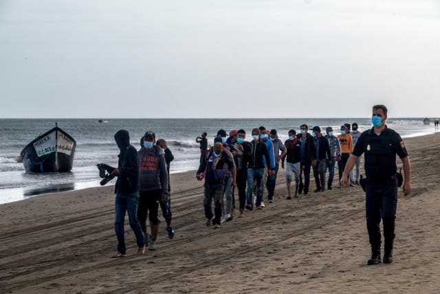 <p>En esta foto del 20 de octubre del 2020, migrantes de Marruecos caminan por la costa acompañados por la policía española tras llegar a la isla de Gran Canaria. El gobierno de España trata apresuradamente de lidiar con el consistente flujo de migrantes de África occidental a las Islas Canarias, abriendo un segundo campamento temporal, dijeron las autoridades el 18 de noviembre, al tiempo que aumentan las tensiones políticas en el archipiélago Atlántico.</p>