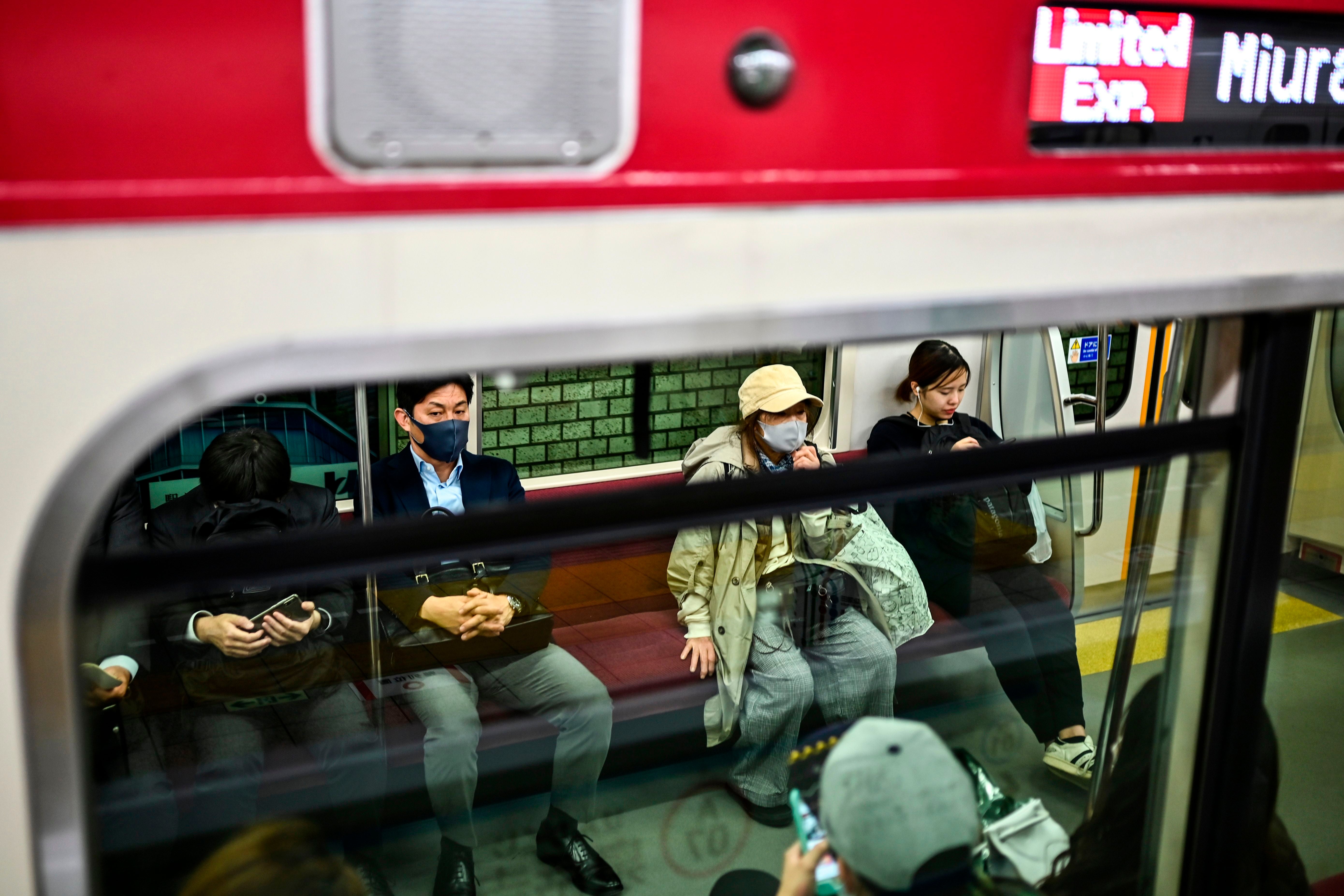 People wear face masks as a preventive measure against the Covid-19 coronavirus, commute late evening in Tokyo on 17 November, 2020.