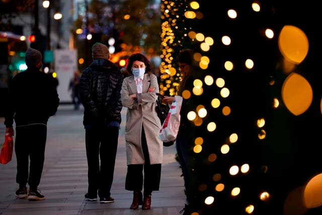 A pedestrian wearing a face mask or covering due to the Covid-19 pandemic, walk past Christmas-themed window display at Selfridges department store in central London on 17 November, 2020.