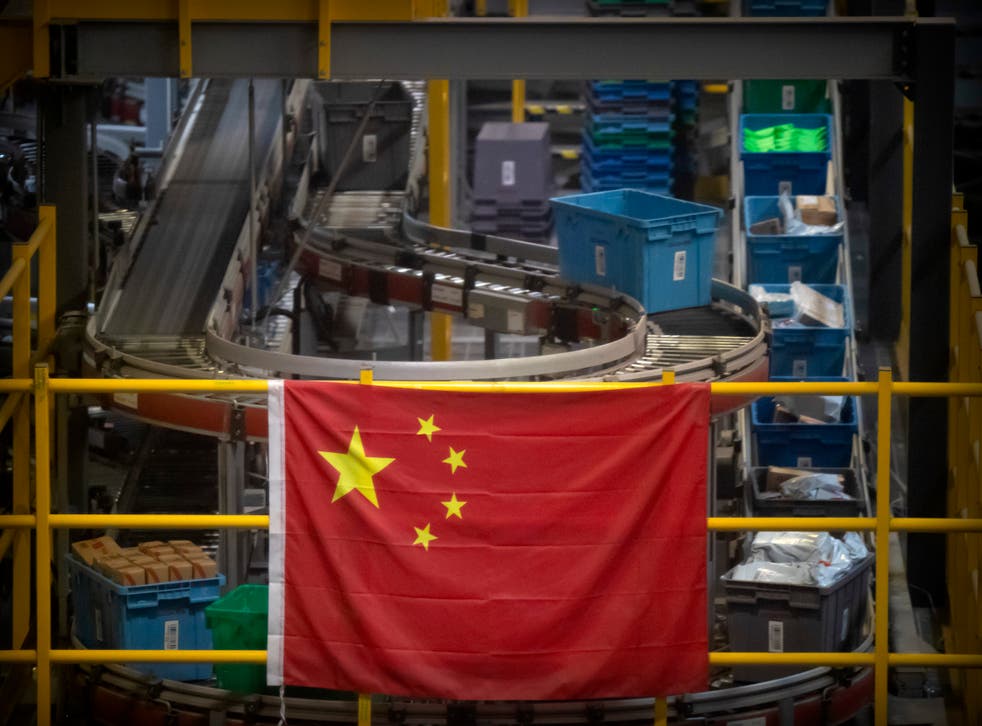 <p>En esta fotografía de archivo del 11 de noviembre de 2020, una bandera china cuelga cerca de una línea de manejo de paquetes en un almacén de un minorista en línea en Beijing. </p>