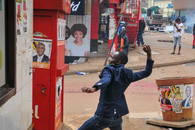 <p>A man prepares to throw a rock during clashes between security forces and protesters supporting Bobi Wine, in Kampala, Uganda</p>