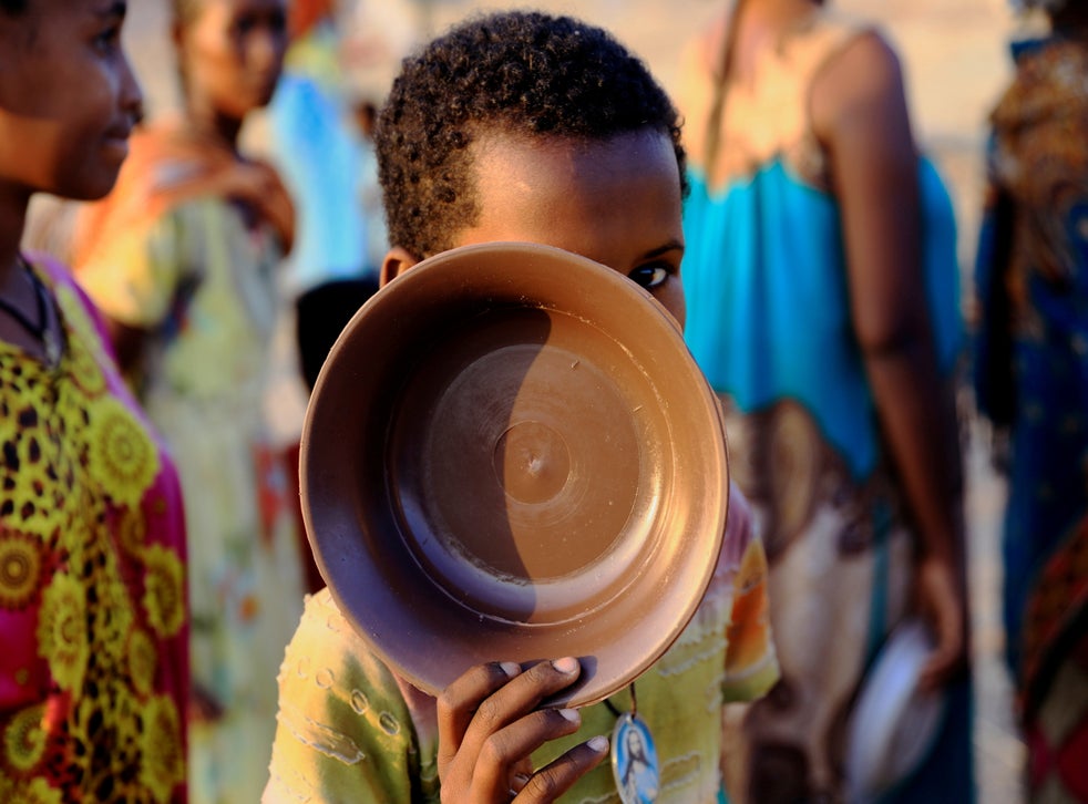 An Ethiopian child who fled war in Tigray region carries his plate as he queues for wet food ration at the Um-Rakoba camp, on the Sudan-Ethiopia border in Al-Qadarif state