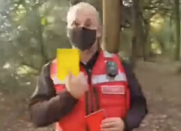 A Covid marshal flashes a yellow card as a warning to people believed to be breaching coronavirus regulations