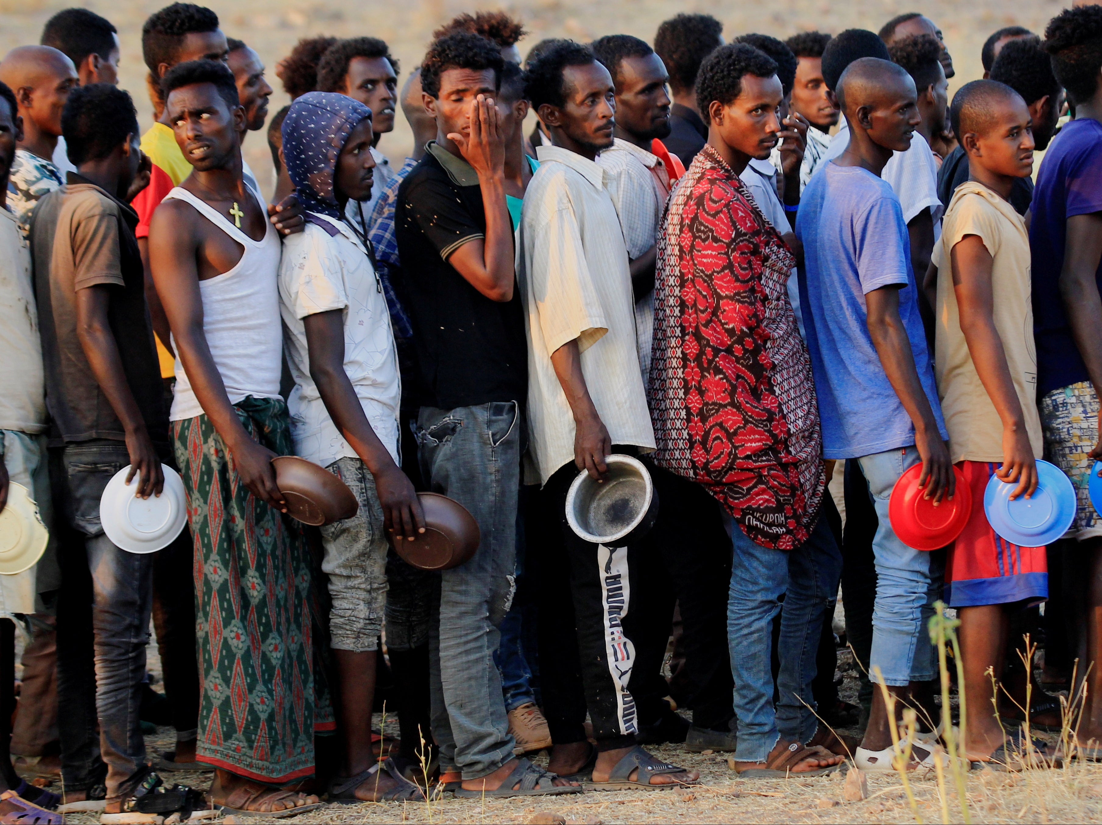 Ethiopian men who fled war in Tigray region queue for food rations at the Um-Rakoba camp