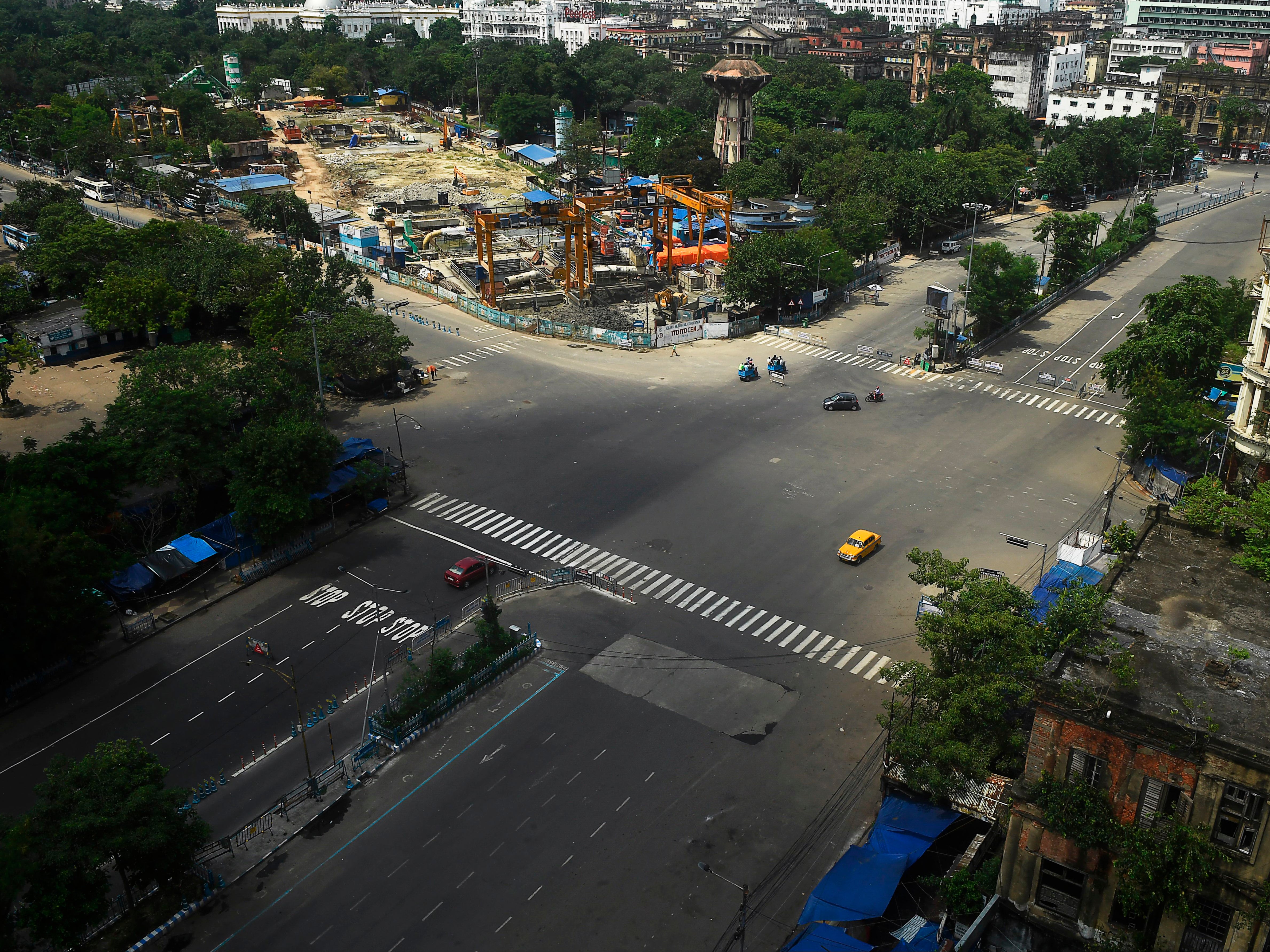 Commuters cross a deserted road during a day-long state-imposed lockdown as a preventive measure against the Covid-19 in Kolkata