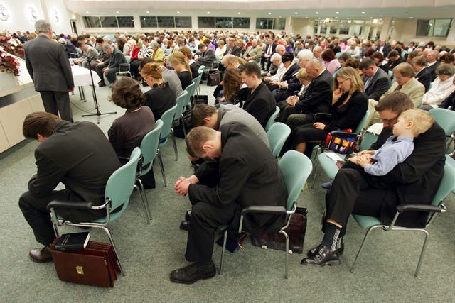 Members of the Jehova's Witnesses Church pray during a religious service 