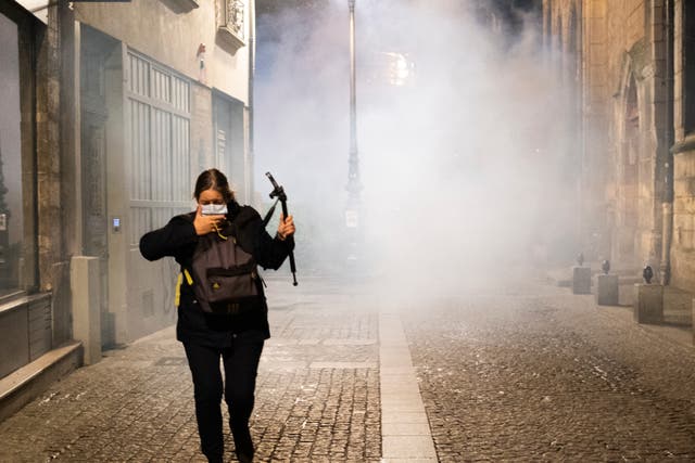 A woman flees tear gas after police removed tents set up by migrants in Paris. Police are under government orders to explain themselves after officers were filmed tossing migrants out of tents while evacuating a makeshift camp in the French capital. (Alexandra Henry/Utopia56 via AP)