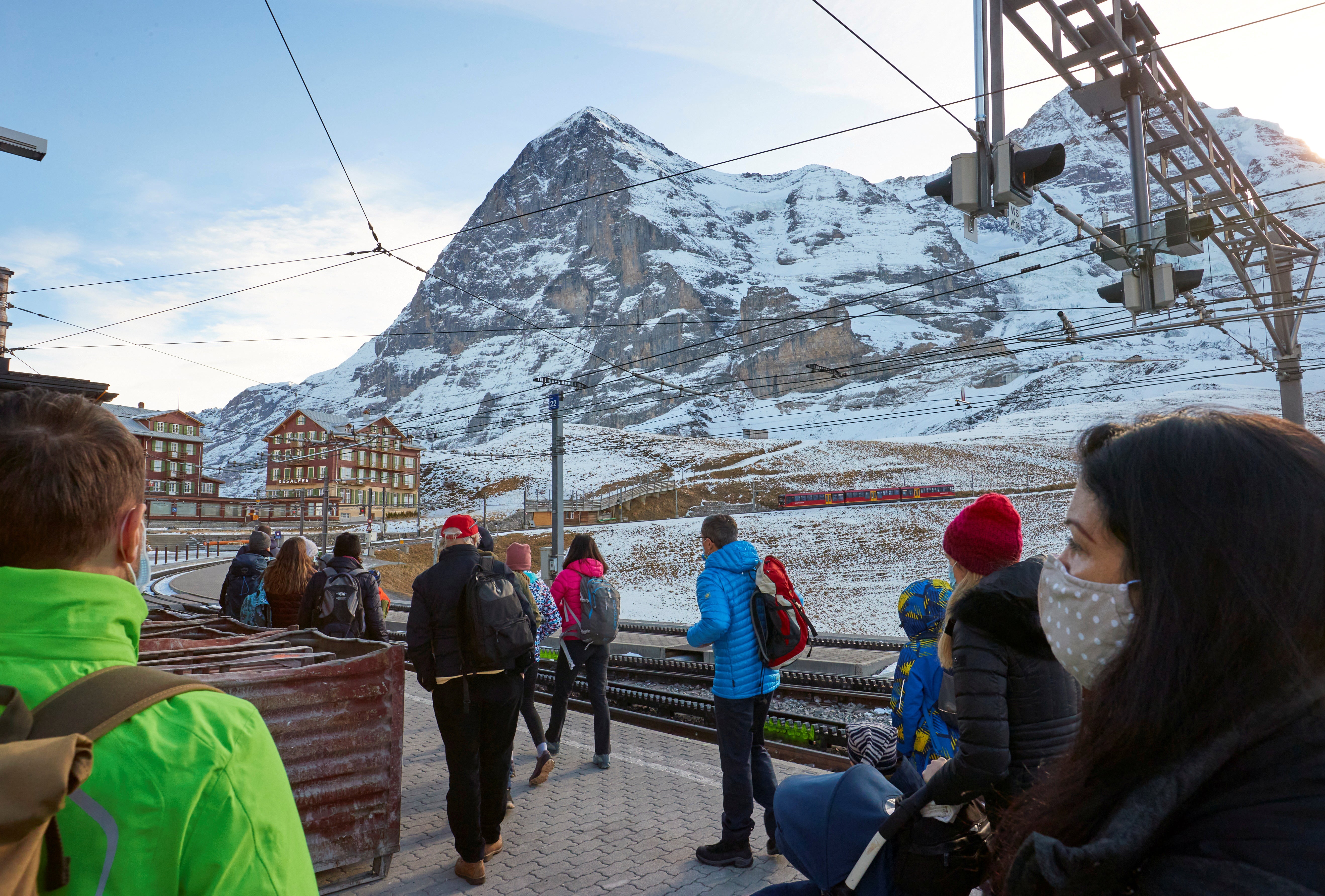 <p>Passengers wearing protective masks wait to board the Jungfraujoch train in the ski resort of Grindelwald, Switzerland</p>