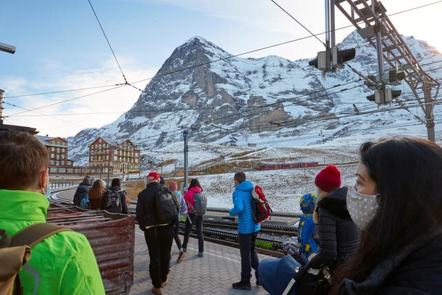 <p>Passengers wearing protective masks wait to board the Jungfraujoch train in the ski resort of Grindelwald, Switzerland</p>