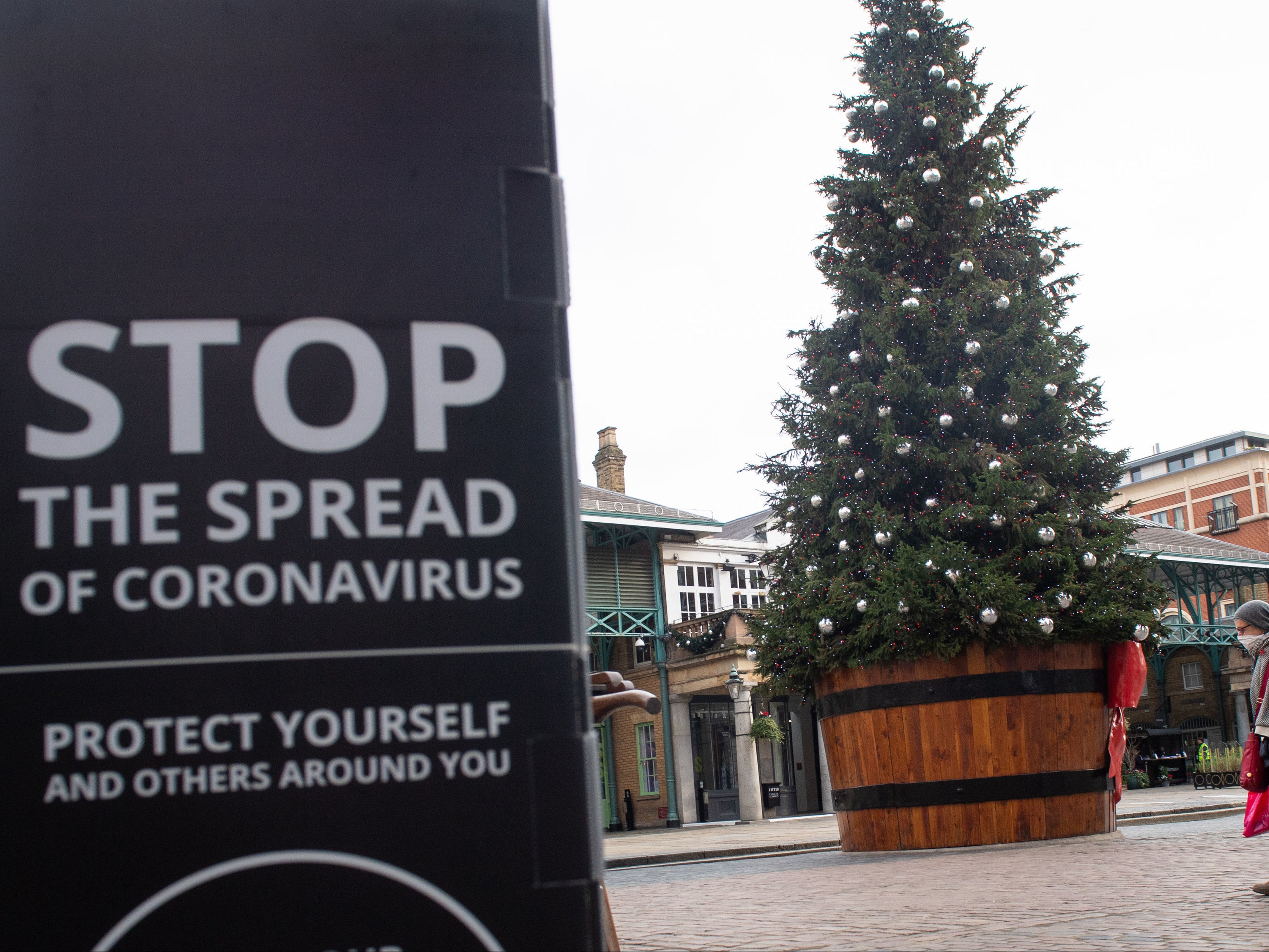A sign warning about coronavirus near a Christmas tree at Covent Garden, London