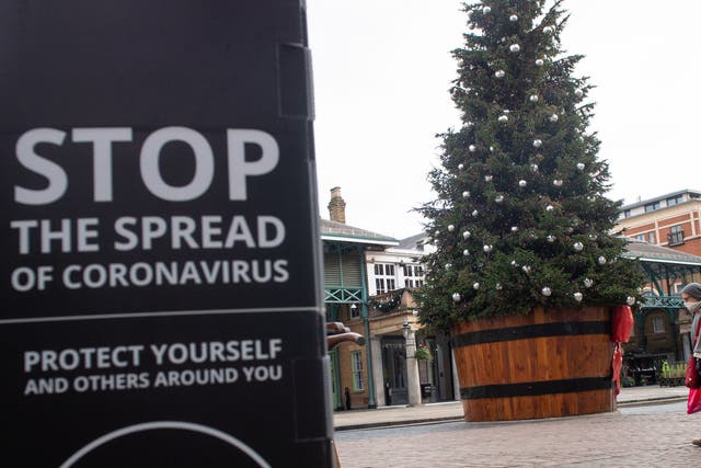 A sign warning about coronavirus near a Christmas tree at Covent Garden, London