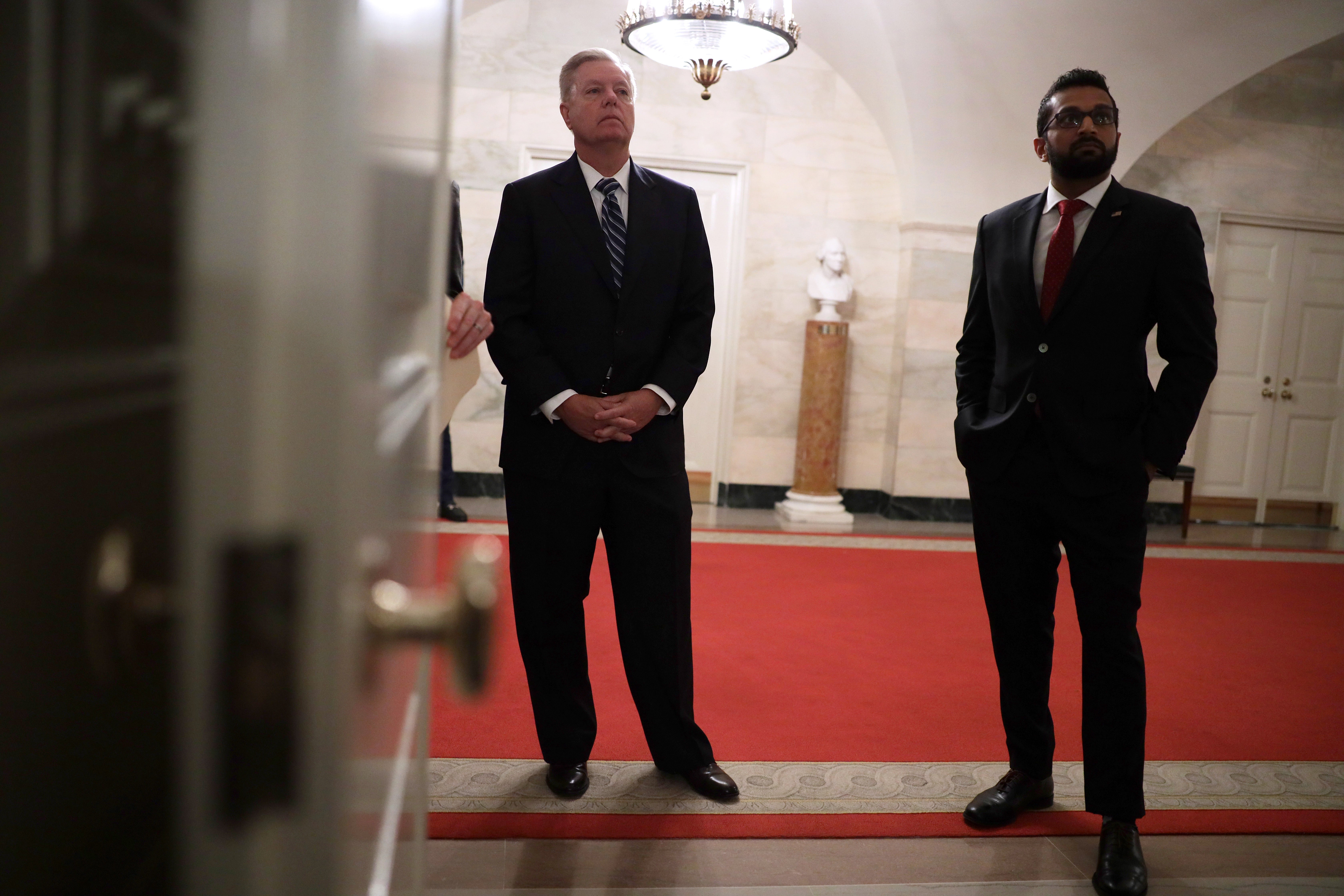 US Senator Lindsey Graham (left) and Kashyap “Kash” Pramod Patel (right) listen as &nbsp;Donald Trump makes a statement in the White House on October 27, 2019&nbsp;