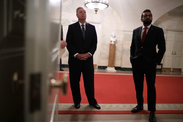 <p>US Senator Lindsey Graham (left) and Kashyap “Kash” Pramod Patel (right) listen as &nbsp;Donald Trump makes a statement in the White House on October 27, 2019&nbsp;</p>