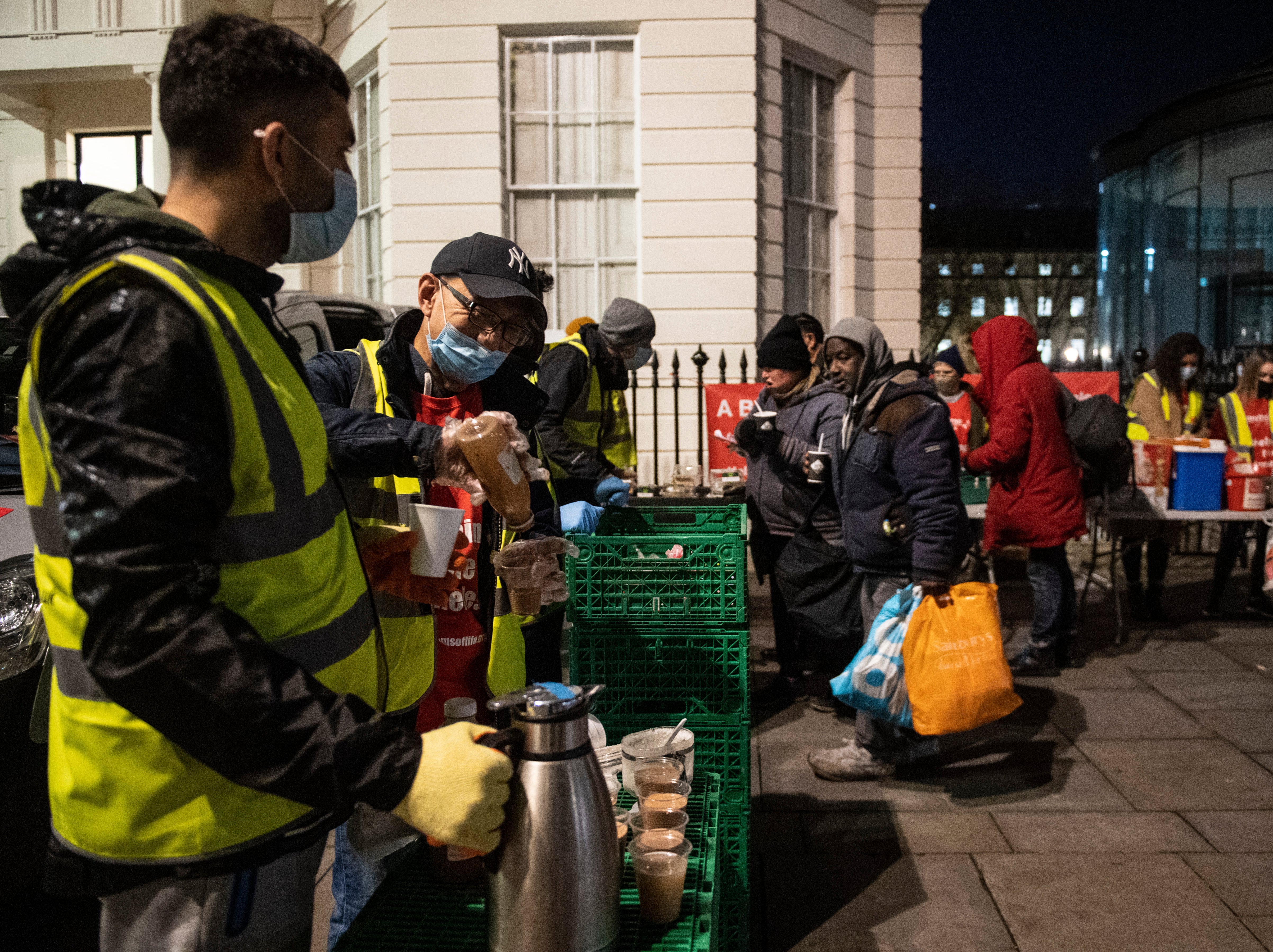 Homeless people collect donated food provided by the Rhythms of Life charity near Trafalgar Square, London