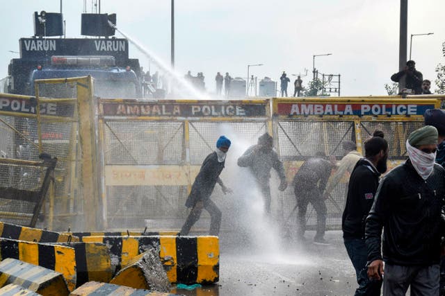 Police block a road and use a water cannon to disperse farmers marching to India’s capital on Thursday