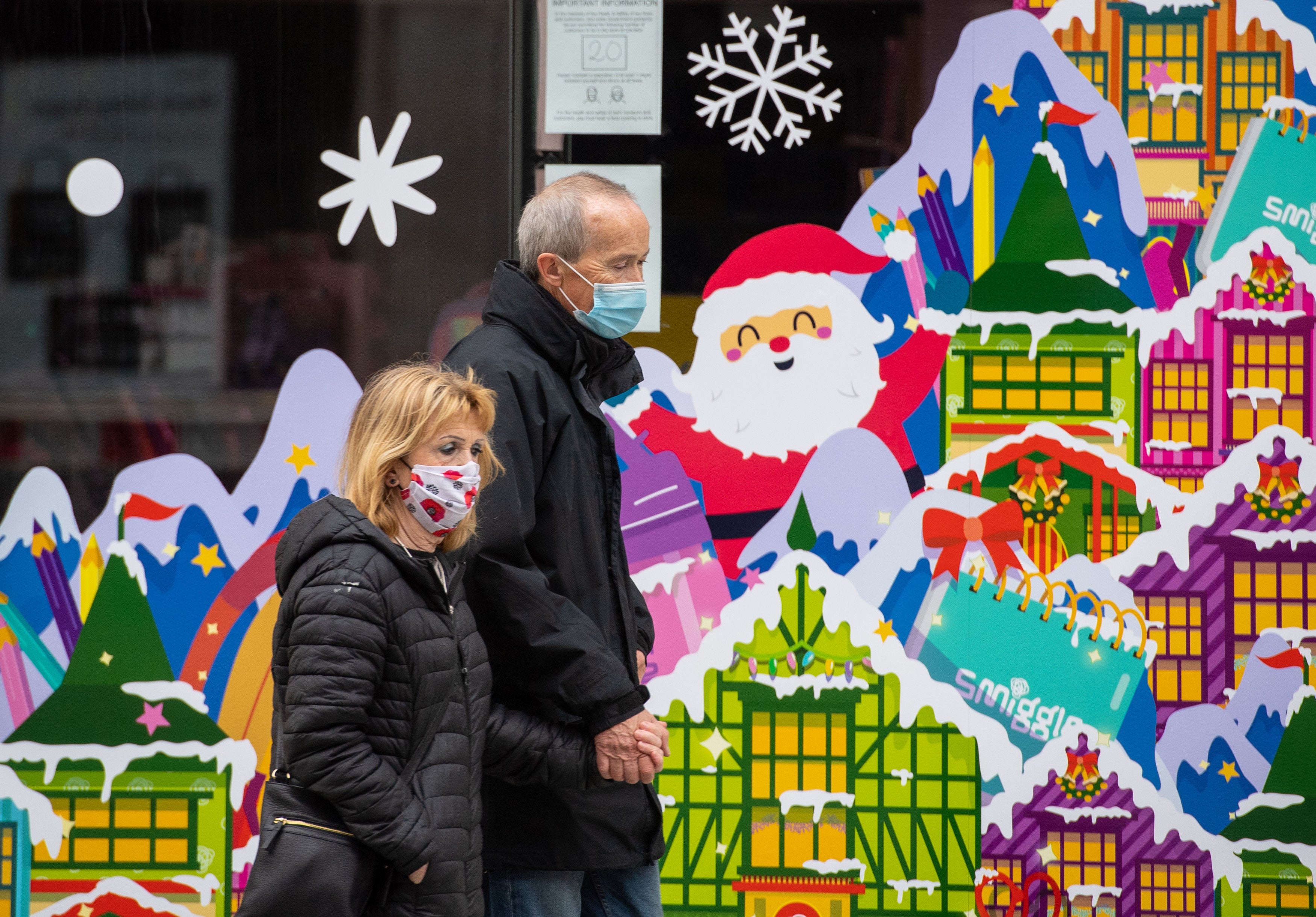 People wearing face masks pass a Christmas window display on Oxford Street, London