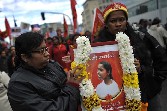 <p>Two women hold a portrait of a casualty of war during a demonstration on September 19, 2011 at the UN's European headquarters in Geneva calling for a probe into alleged war crimes committed by Sri Lanka&nbsp;</p>