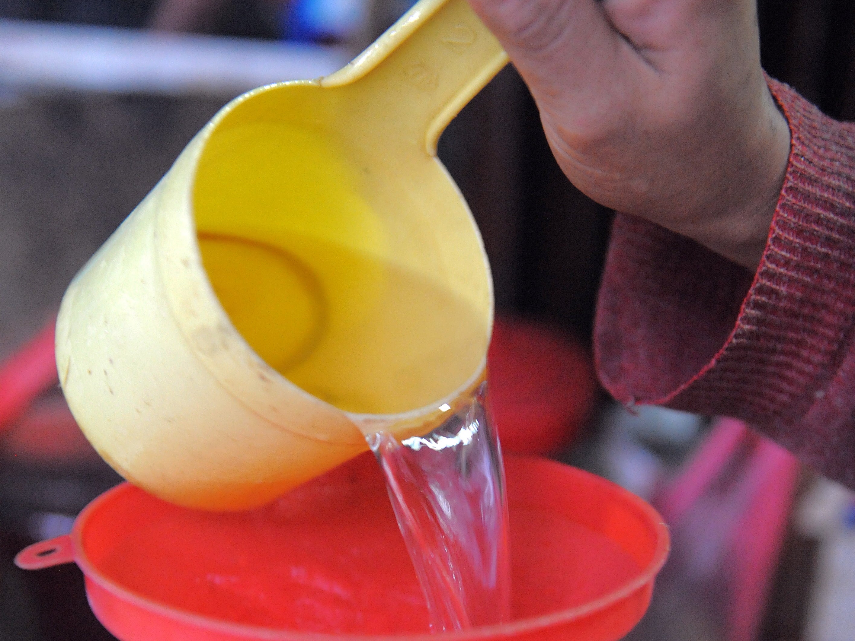 A Cambodian woman decants rice wine into a water bottle for sale in Phnom Penh