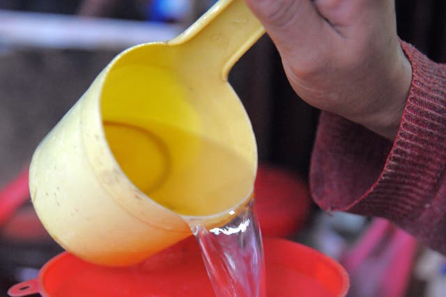 A Cambodian woman decants rice wine into a water bottle for sale in Phnom Penh