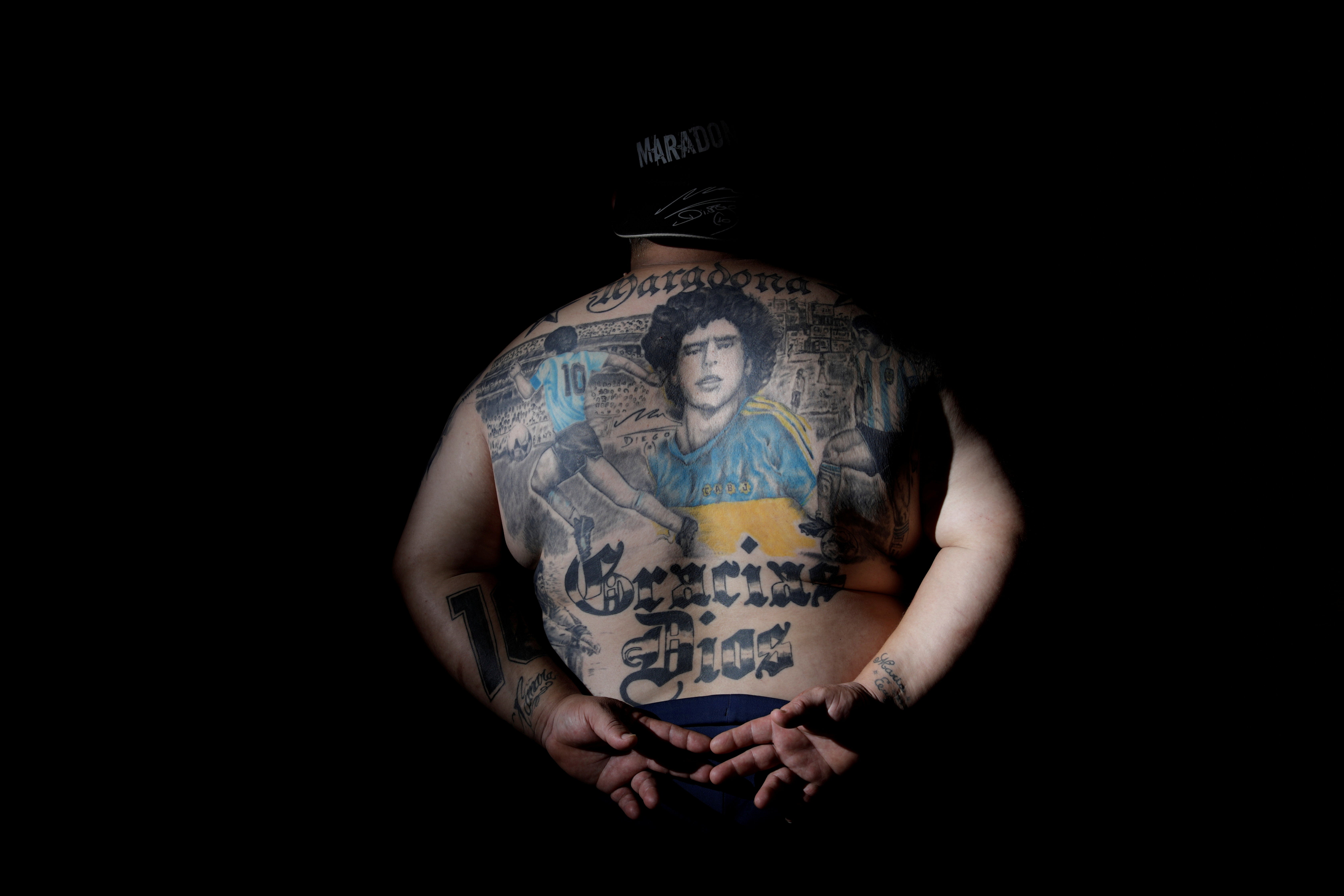 Guillermo Rodriguez, a devoted Diego Maradona fan, shows his tattoos at his pizza shop in Buenos Aires