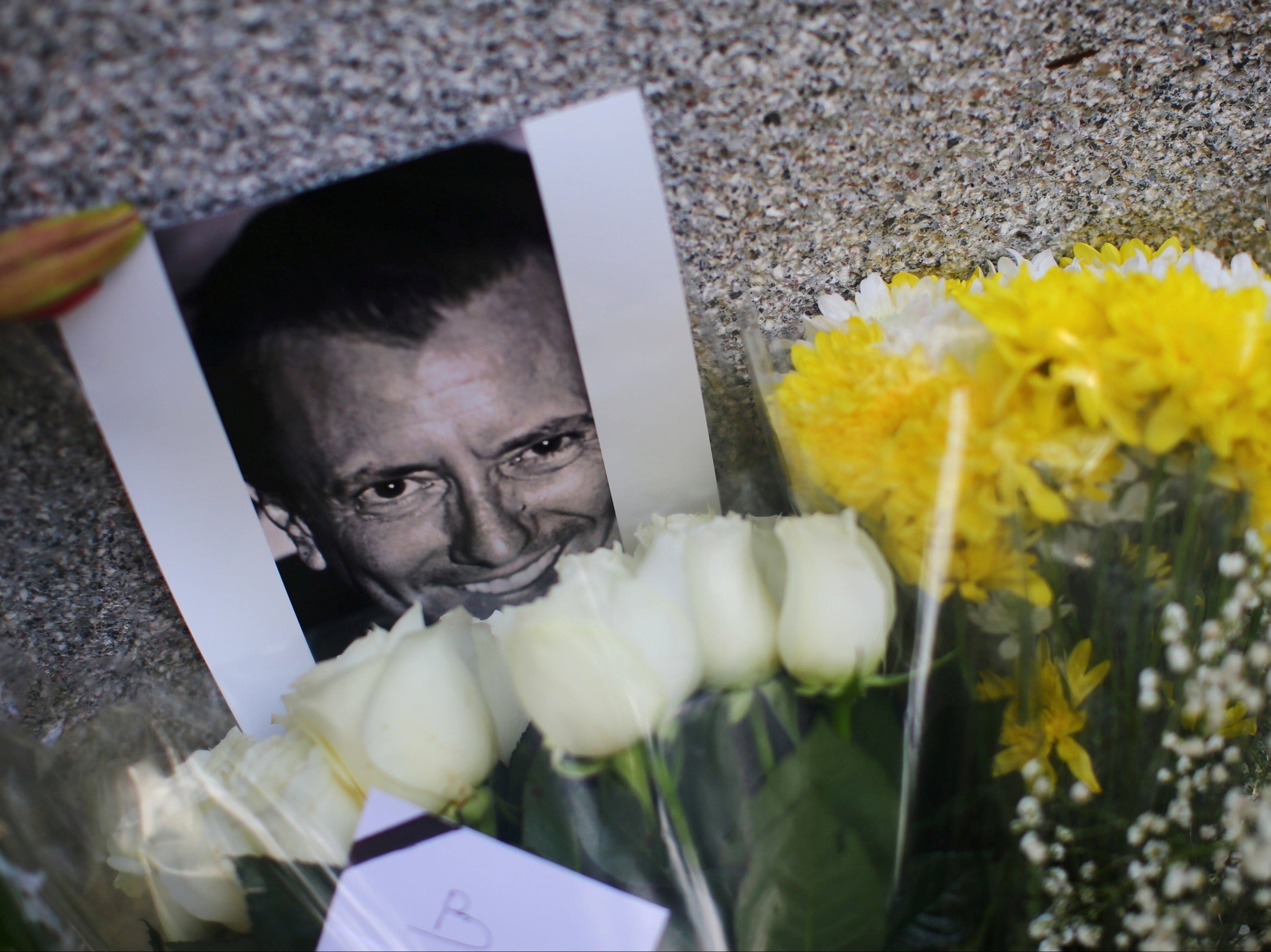 An image of French restaurateur Baptiste Lormand is pictured alongside floral tributes outside the French embassy in Mexico City