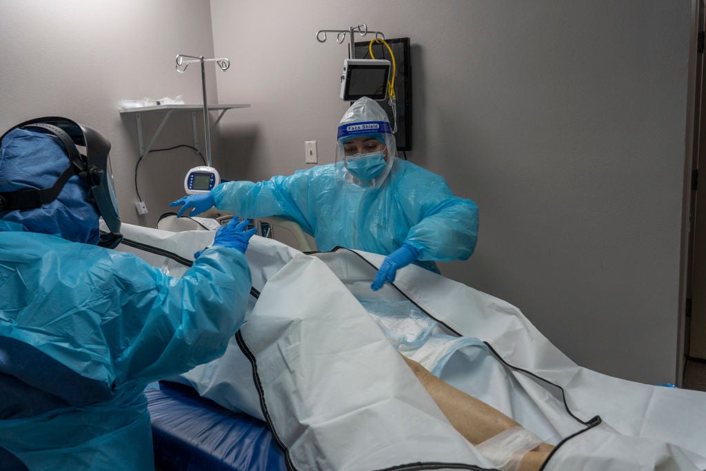 Medical staff at a hospital in Houston, Texas, close the body bag of a deceased Covid-19 patient