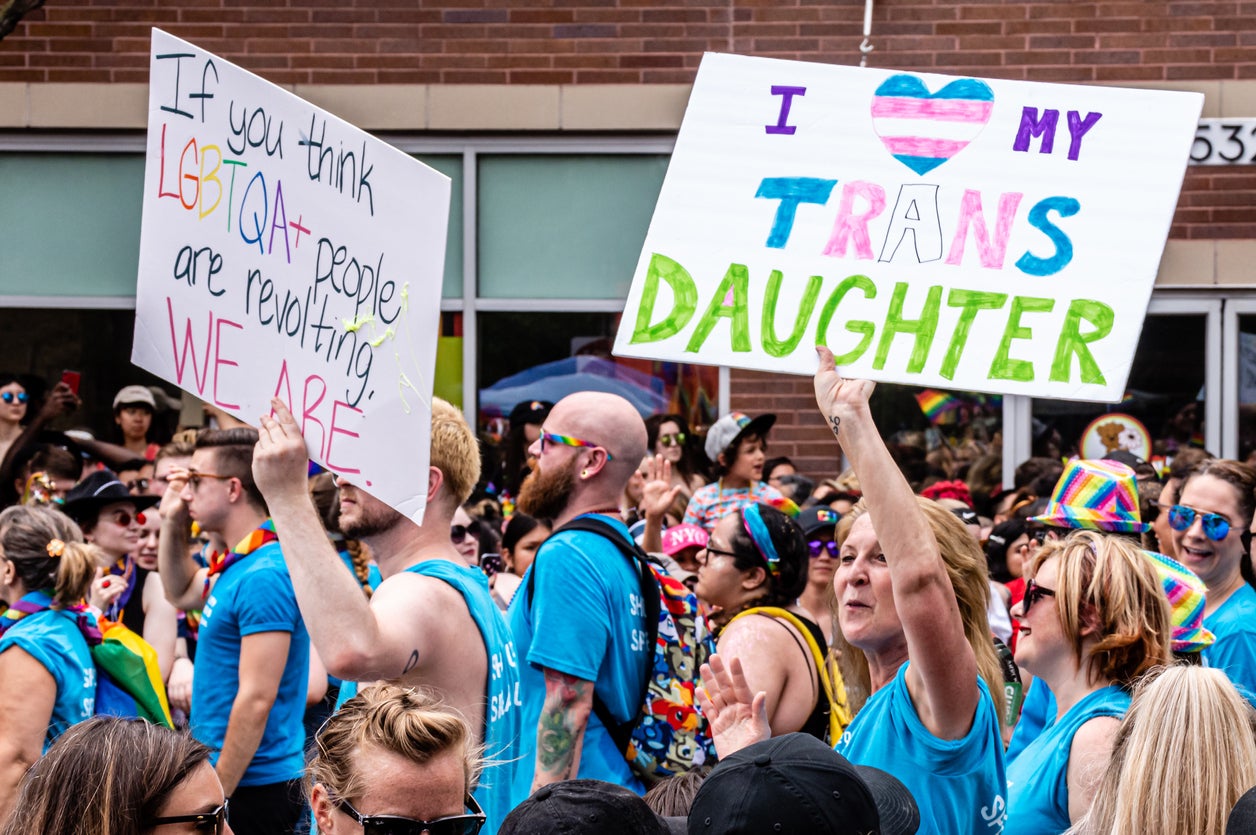 A mother carries a sign that reads, ‘I my trans daughter’ while marching in the Gay Pride parade