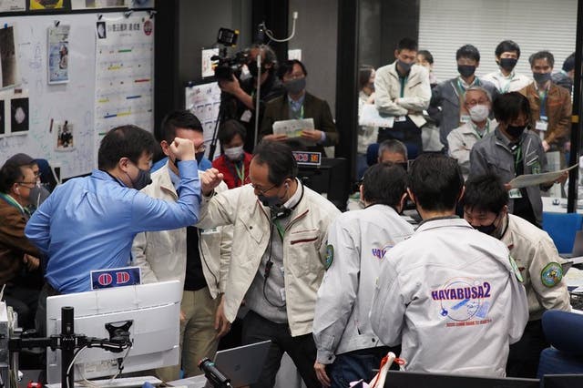 Miembros del equipo celebran el éxito de una maniobra de la sonda espacial japonesa Hayabusa2, en el control de la misión, en el Campus Sagamihara de JAXA en Sagamihara, cerca de Tokio, el 5 de diciembre de 2020. 