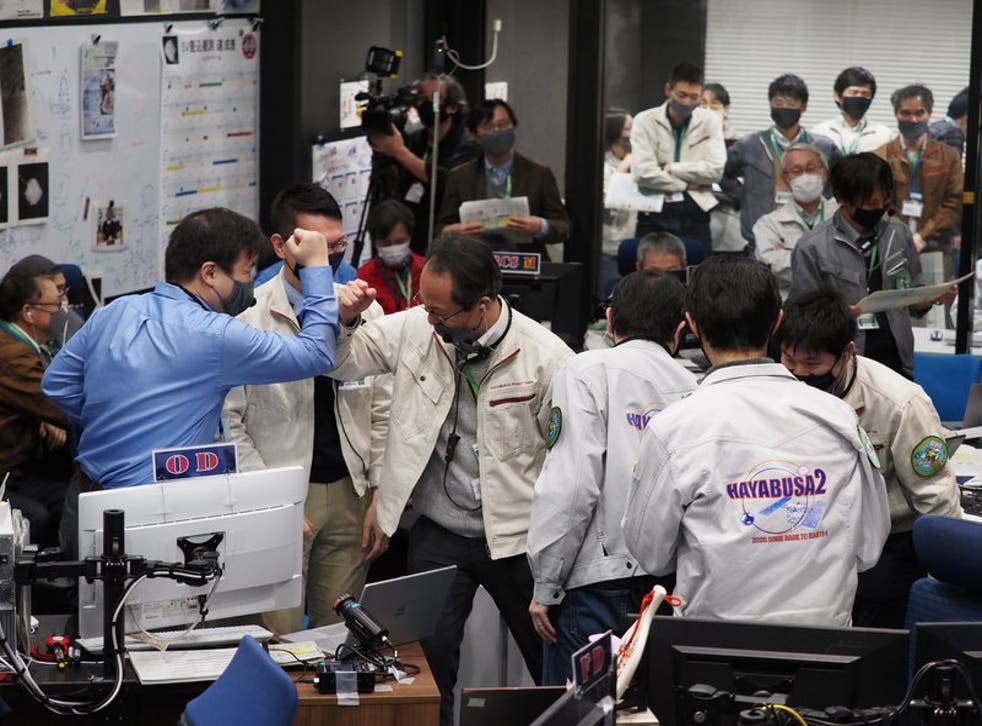 Miembros del equipo celebran el éxito de una maniobra de la sonda espacial japonesa Hayabusa2, en el control de la misión, en el Campus Sagamihara de JAXA en Sagamihara, cerca de Tokio, el 5 de diciembre de 2020.