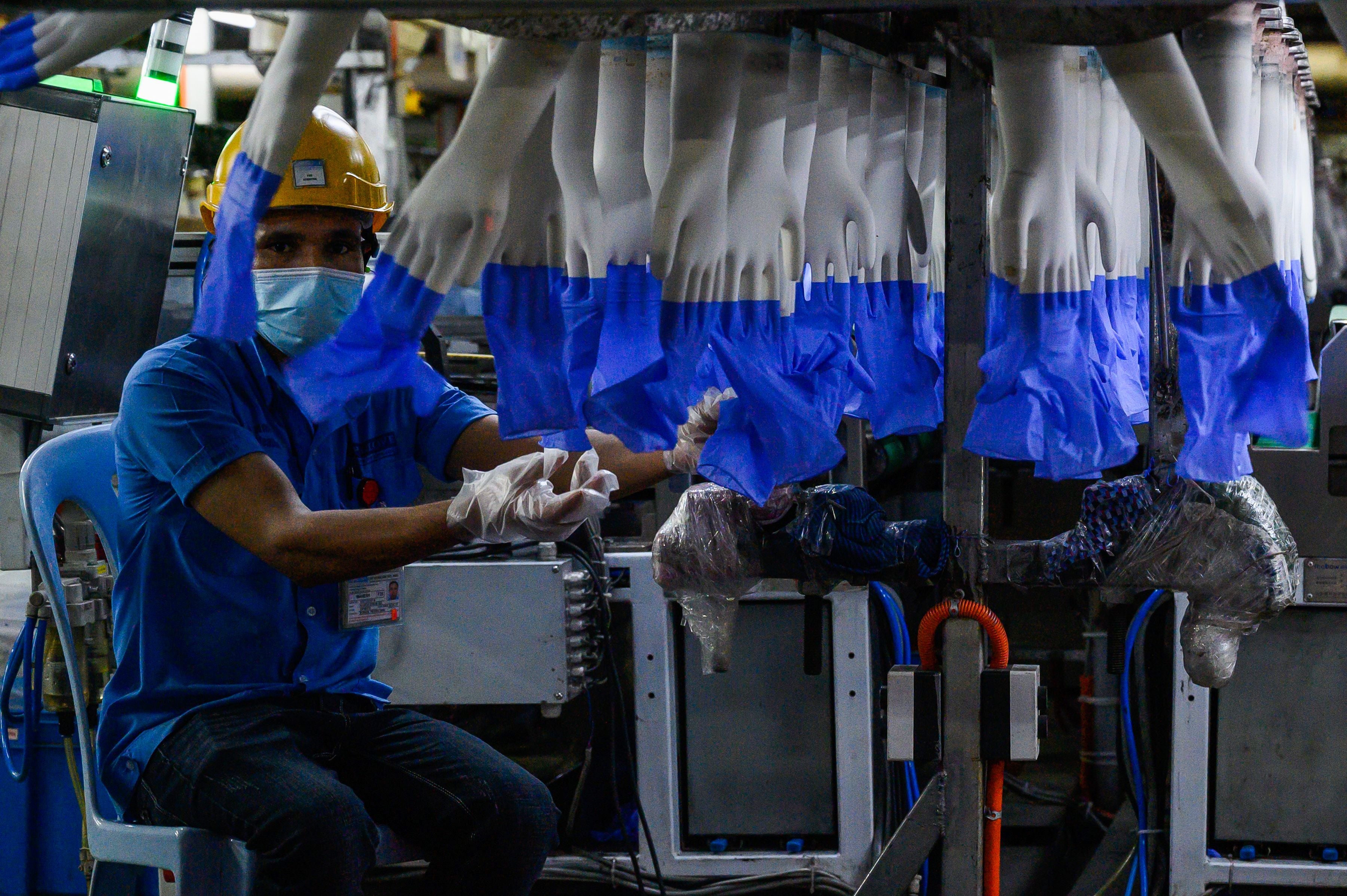 A worker inspects disposable gloves at the Top Glove factory in the outskirts of Kuala Lumpur