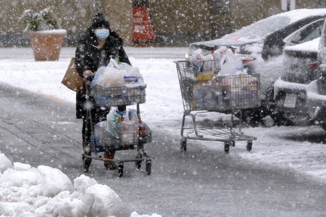 Una persona transporta comestibles en un carrito bajo una fuerte nevada en un estacionamiento en Marlborough, Massachusetts, el sábado 5 de diciembre de 2020. 