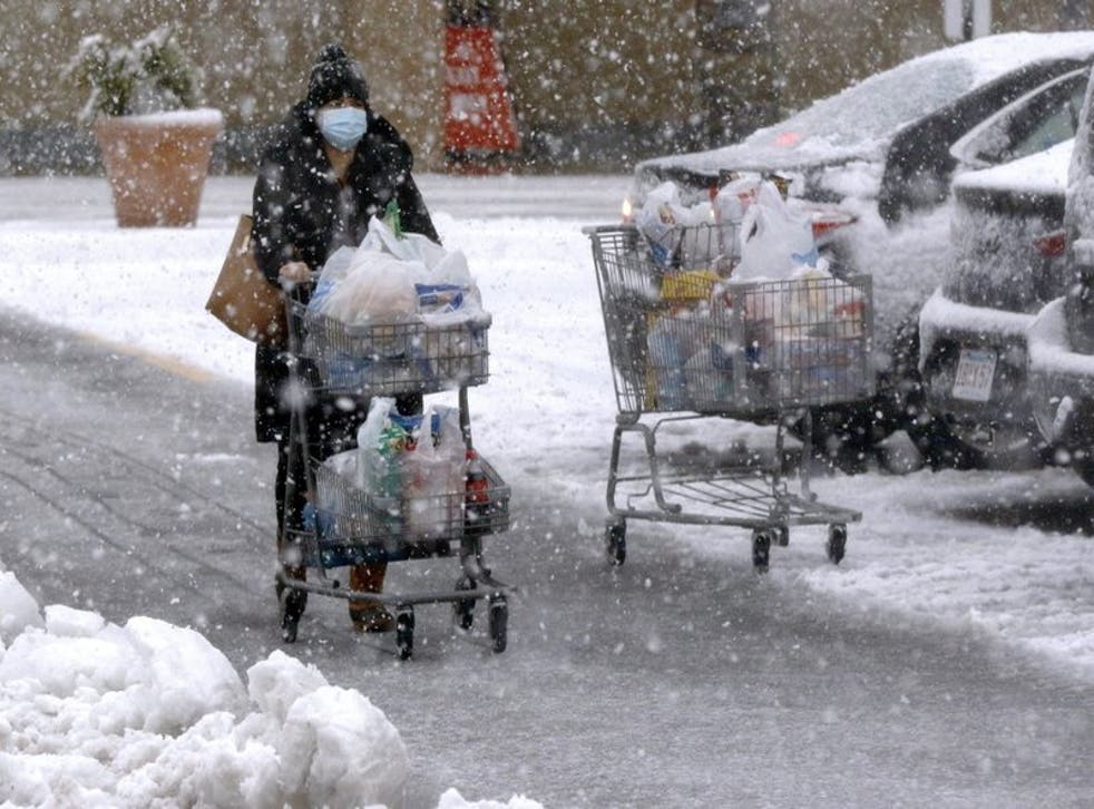 Una persona transporta comestibles en un carrito bajo una fuerte nevada en un estacionamiento en Marlborough, Massachusetts, el sábado 5 de diciembre de 2020.