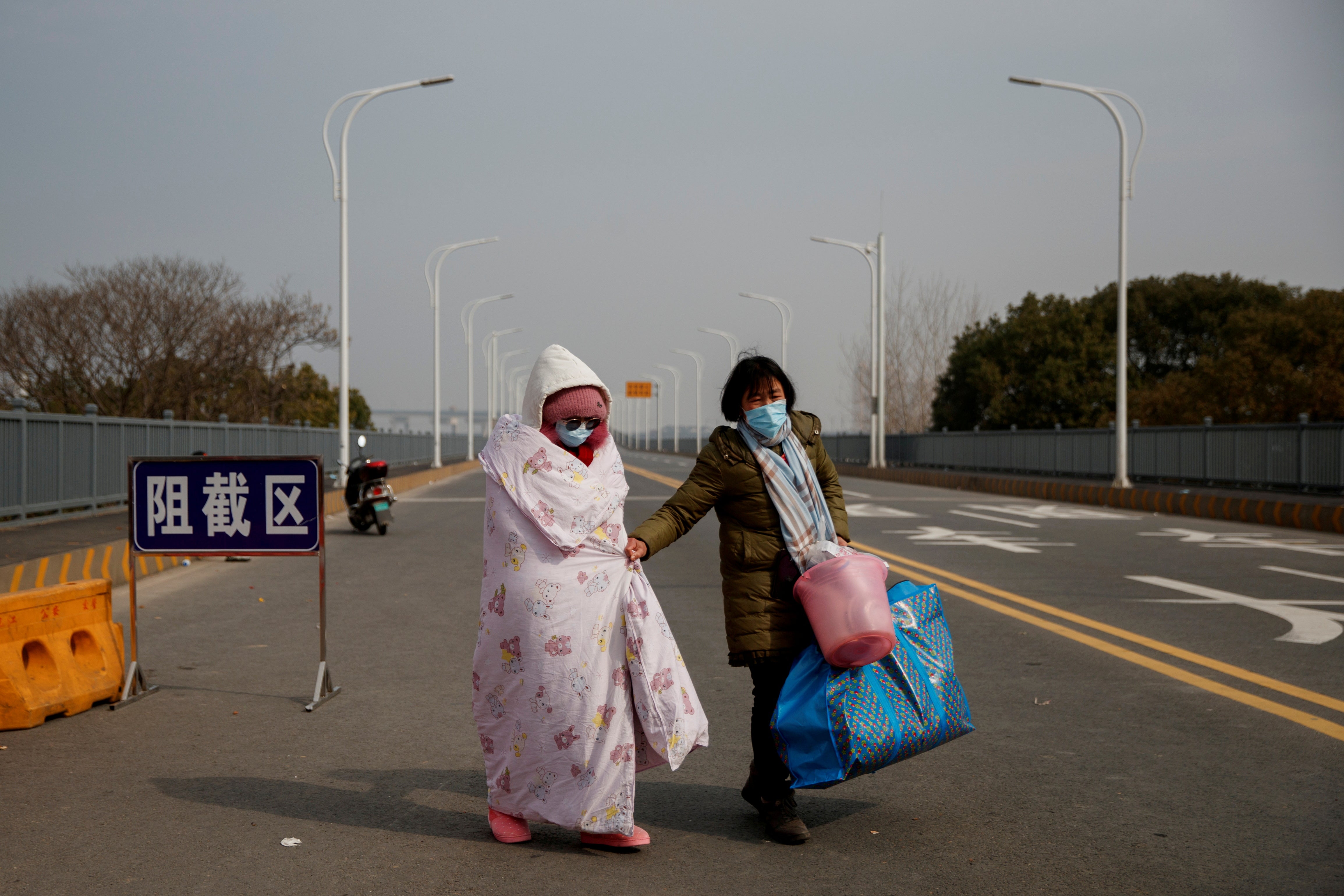 Leukaemia patient Hu Ping and her mother cross a checkpoint at the Jiujiang Yangtze River Bridge in China in February