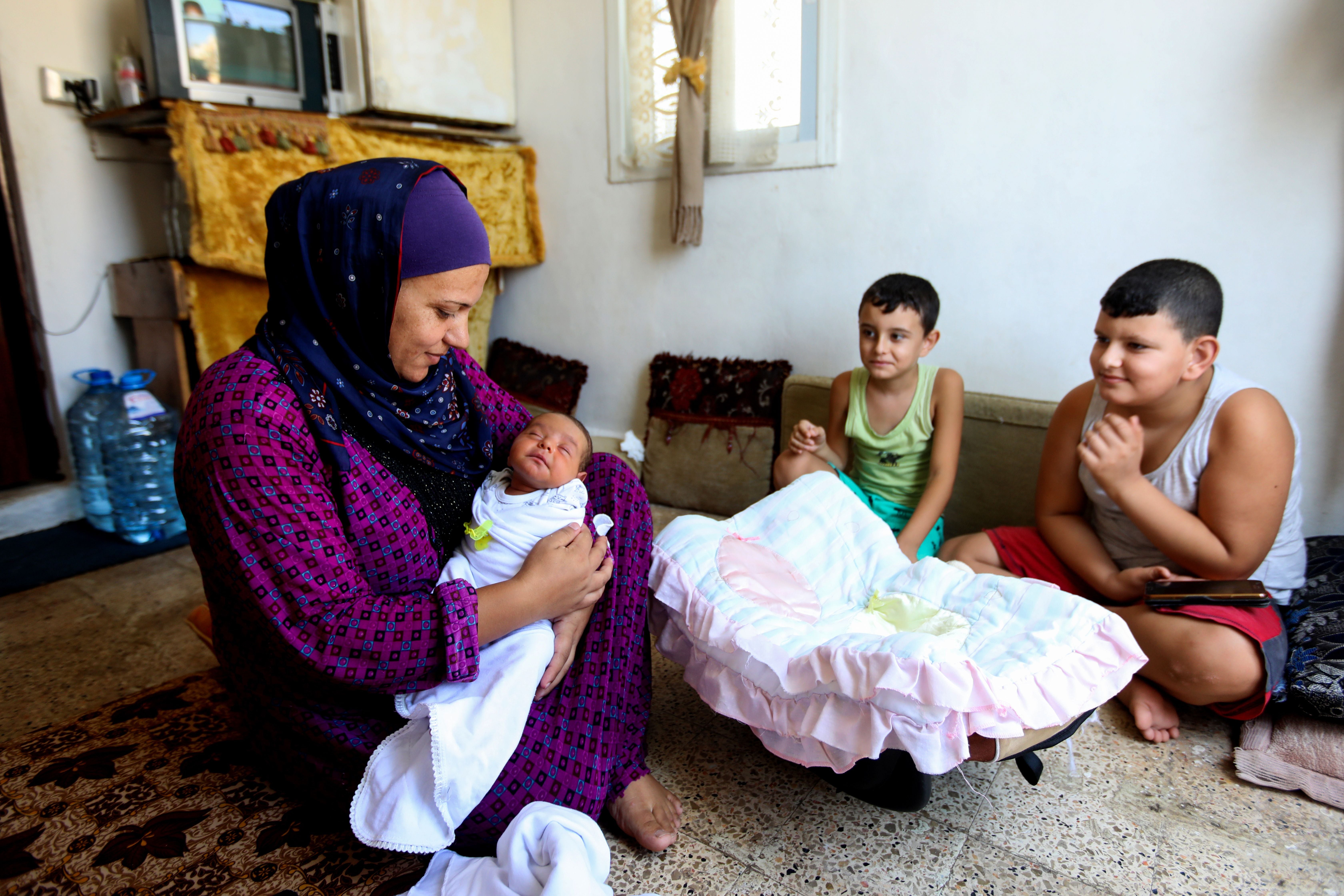 Syrian refugee Rima Jassem holds her newborn girl as she sits with her boys in a small room on the roof of a building overlooking the ravaged port in Lebanese capital Beirut, on September 18, 2020. Refugees living in affected areas in Beirut have also been impacted by the August explosion.