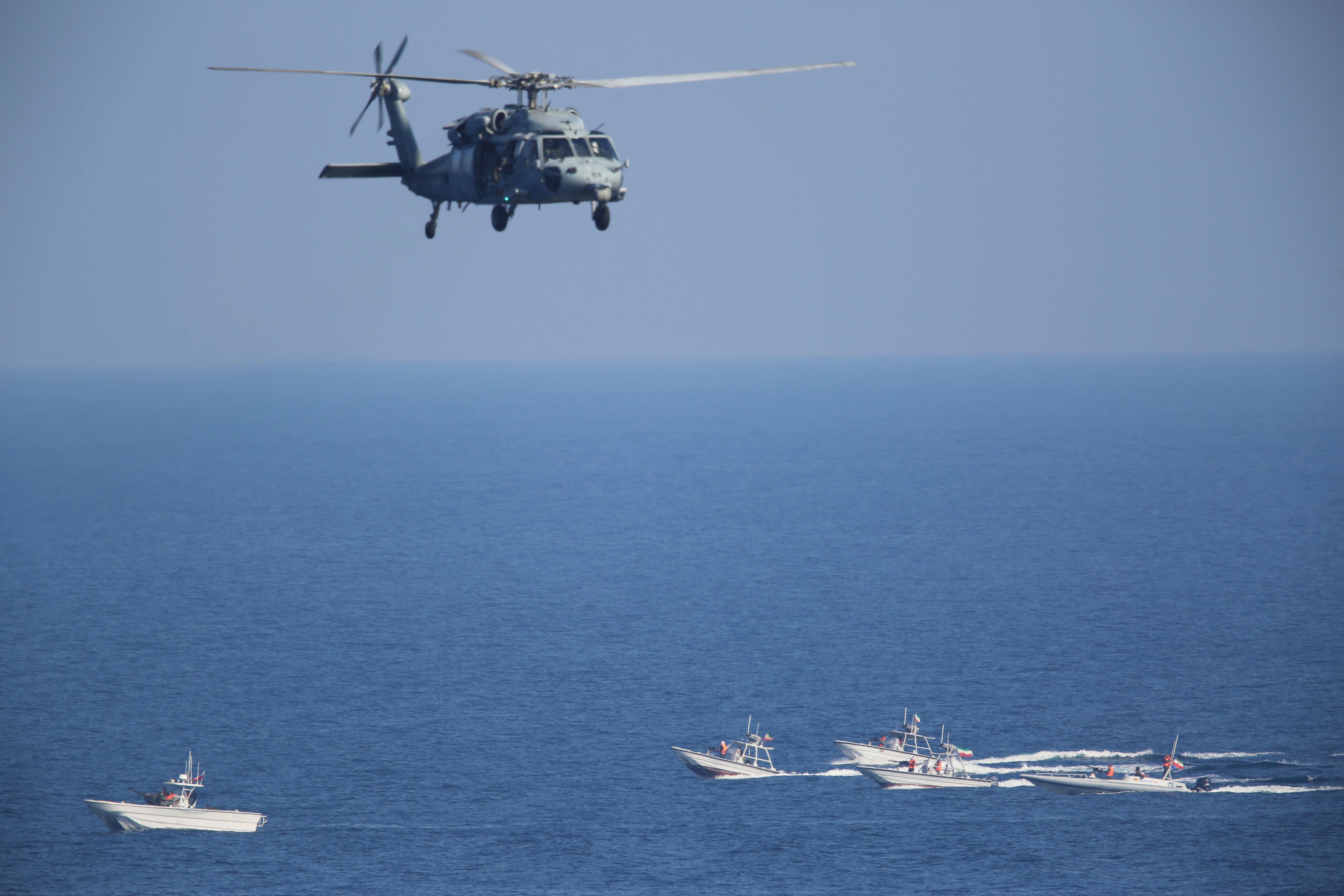 A US MH-60 Seahawk helicopter flies over Iranian Revolutionary Guard patrol boats in the Strait of Hormuz (AP Photo/Jon Gambrell, File)