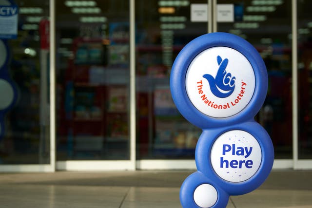 Blue National Lottery sign, showing its crossed fingers logo, in front of shop entrance