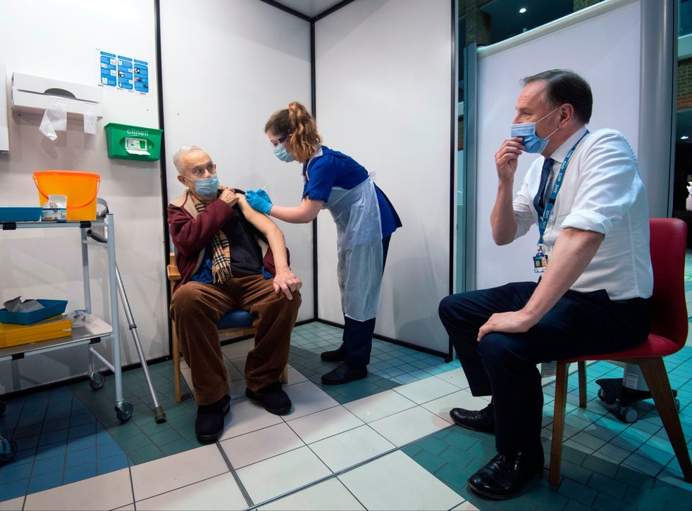 Simon Stevens, NHS England chief executive, watches as a nurse administers a dose of Covid-19 vaccine to 82-year-old Frank Naderer