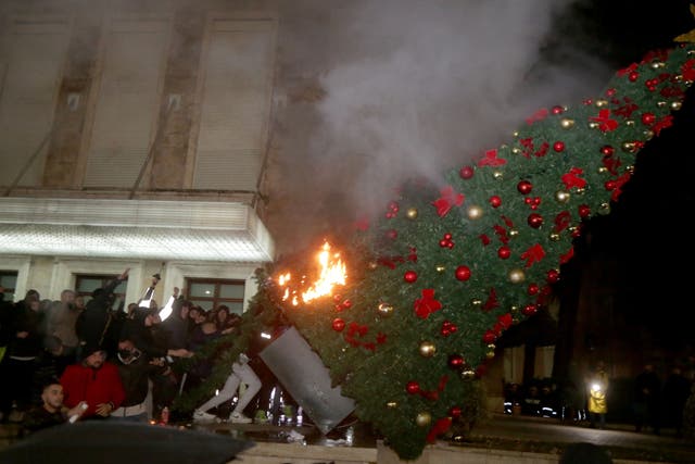 Protesters burn a Christmas tree in front of the Albanian Prime Minister building during clashes in Tirana