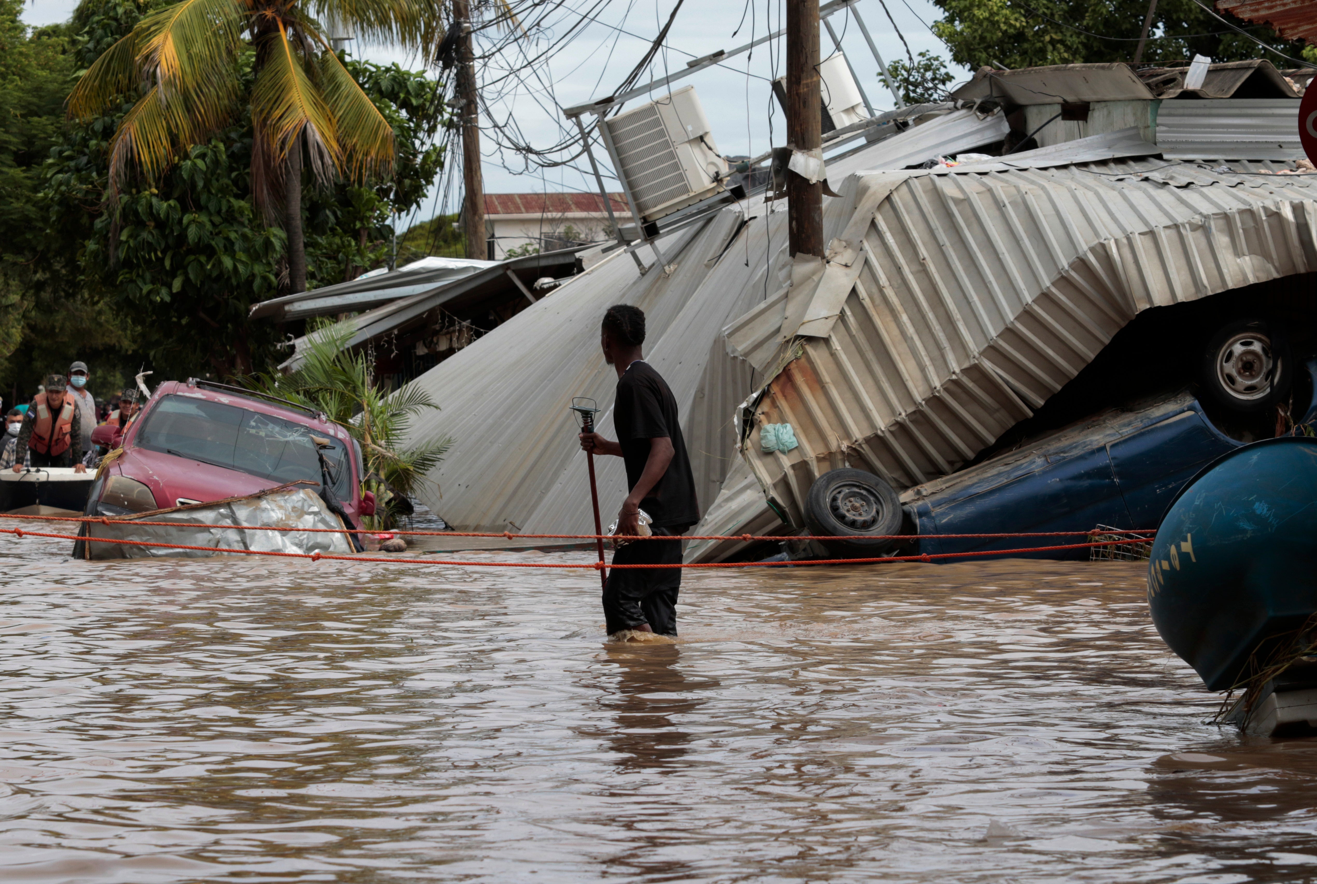 In this Nov. 6, 2020, file photo, a resident walking through a flooded street looks back at storm damage caused by Hurricane Eta in Planeta, Honduras