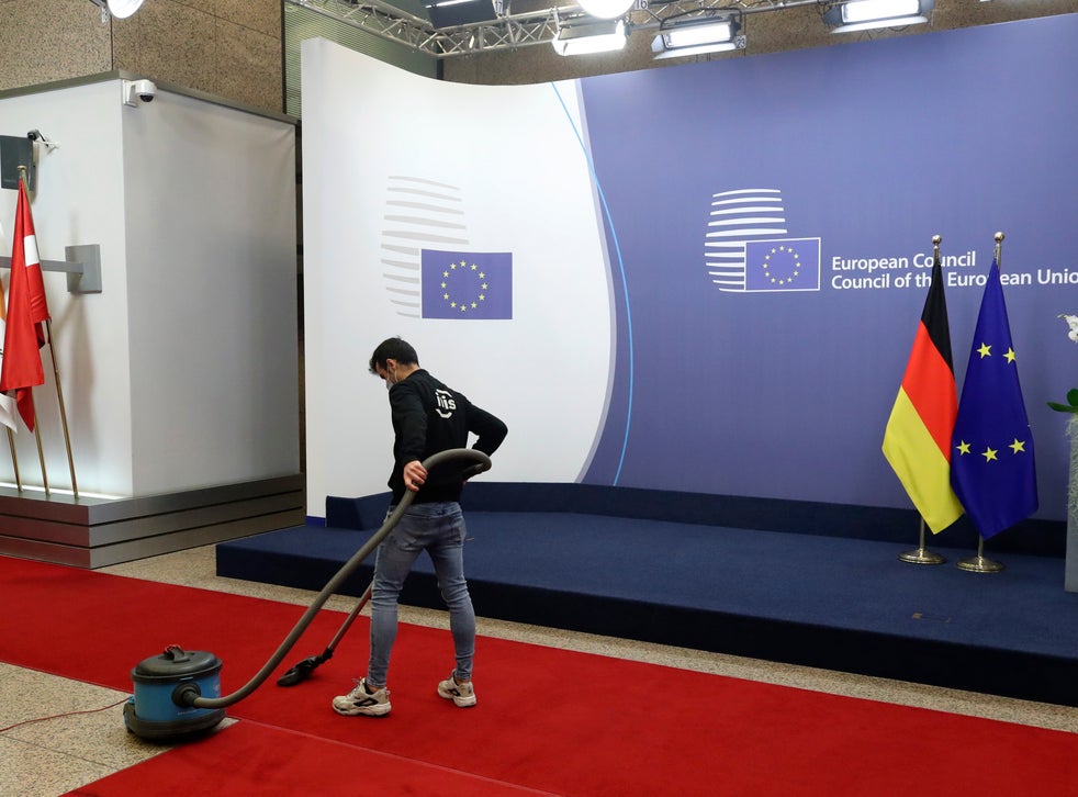 A worker is seen vacuuming a carpet ready for the summit’s second day of proceedings