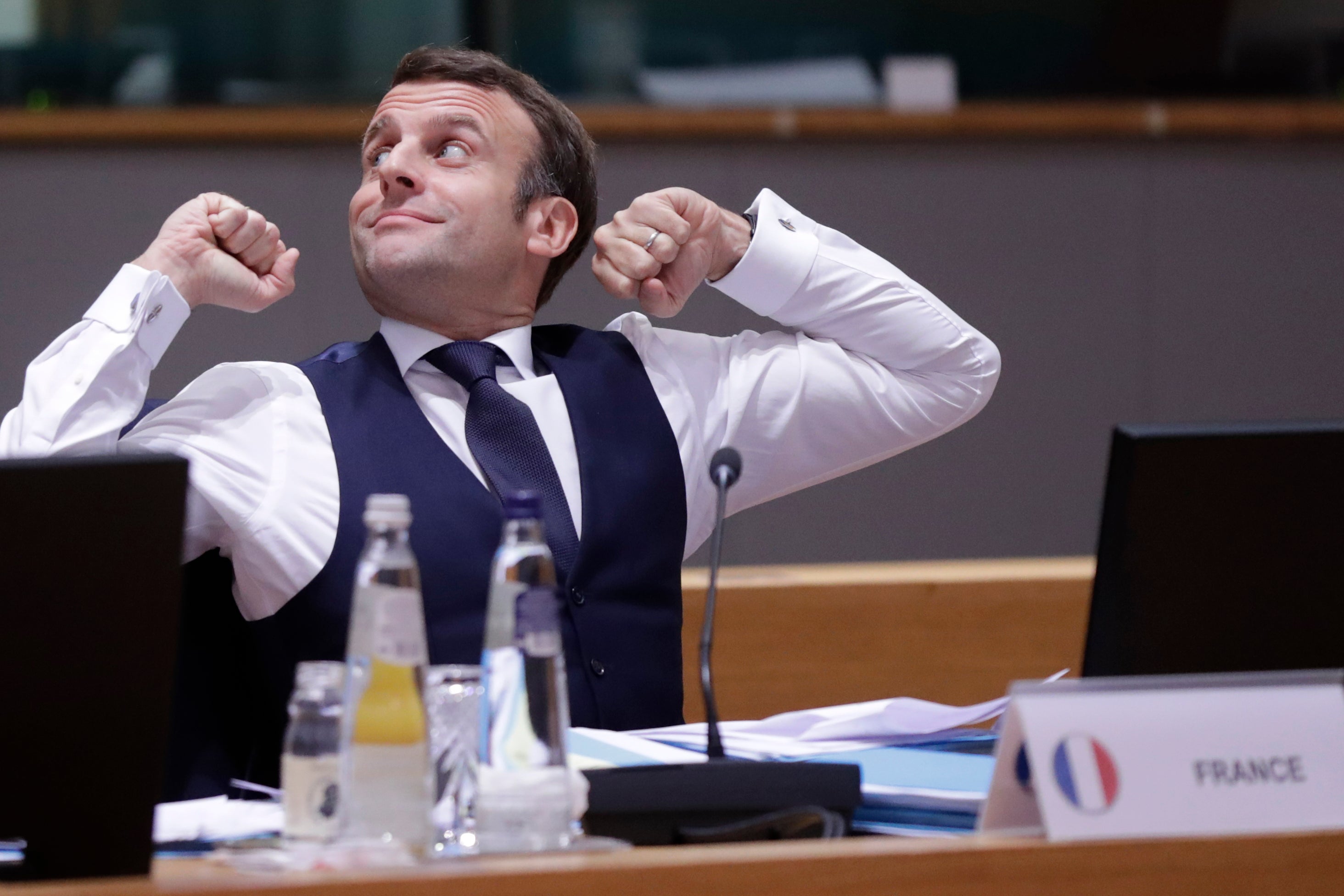 France’s President Emmanuel Macron stretches after a night of negociation during a round table meeting in the EU summit