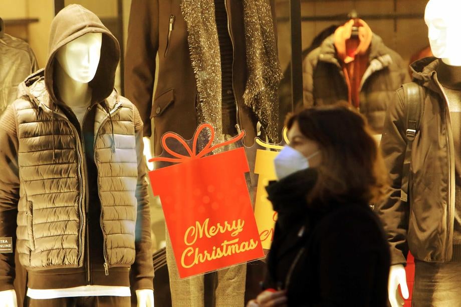 A woman walks past Christmas-themed shopping windows in Milan