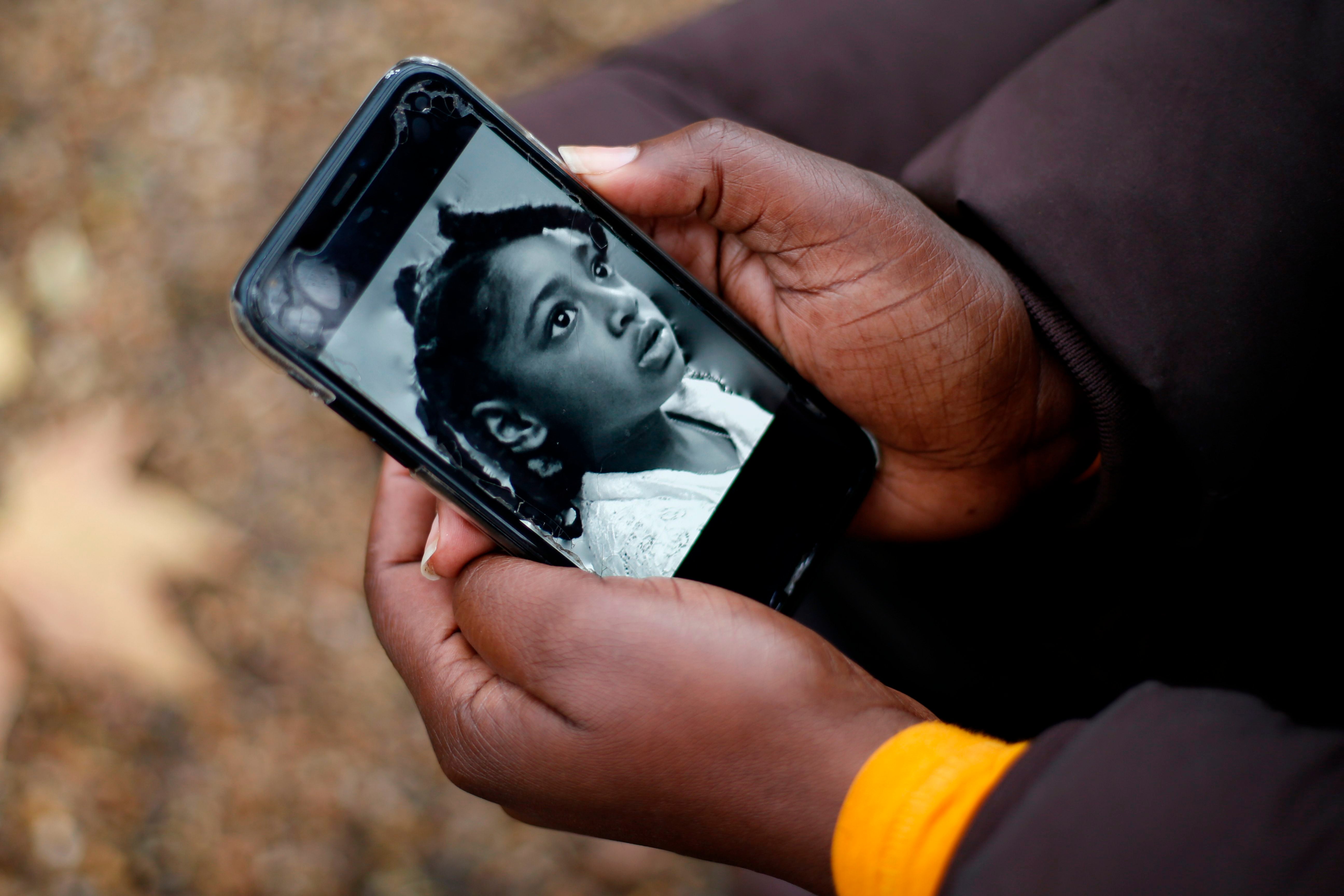 Rosamund Adoo-Kissi-Debrah holds her mobile phone displaying a photograph of her daughter